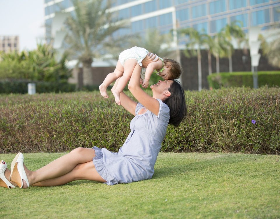 Madre sonriendo mientras sostiene a su bebé, representando el vínculo y la felicidad en la maternidad.