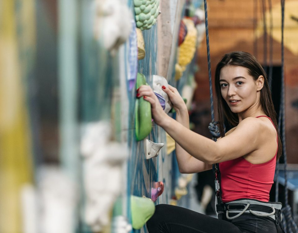 Una mujer sonriente escalando una montaña como metáfora del autocontrol y la superación personal para alcanzar una vida plena