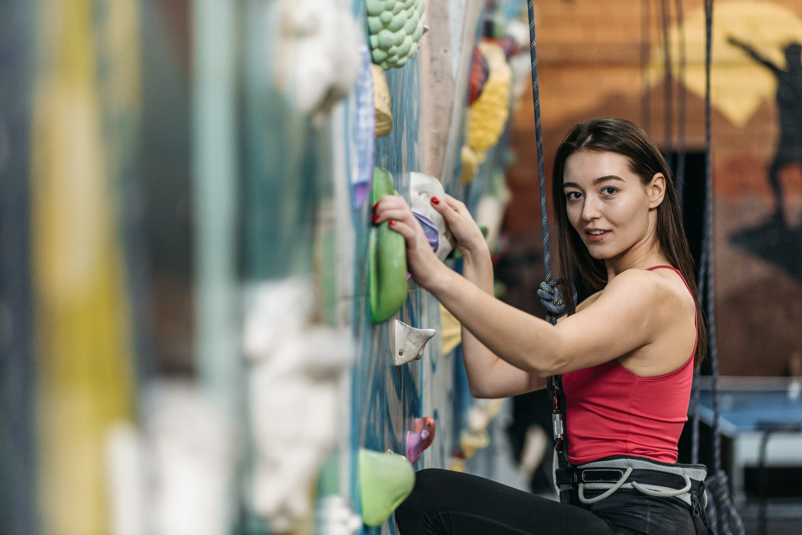 Una mujer sonriente escalando una montaña como metáfora del autocontrol y la superación personal para alcanzar una vida plena