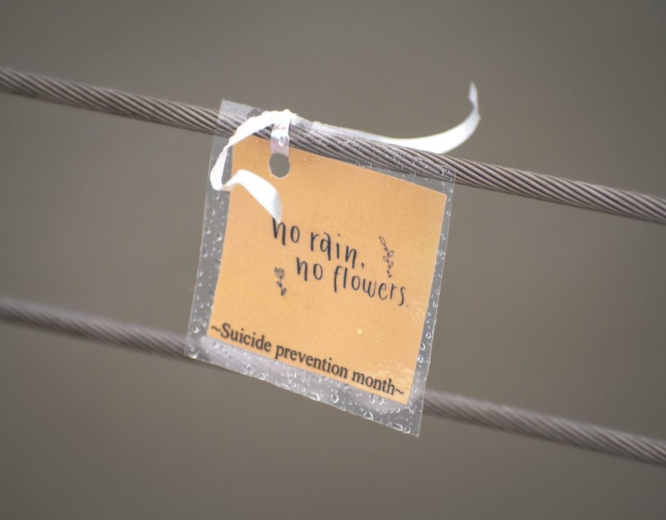 Imagen con una nota que dice 'No rain, no flowers - Suicide Prevention Month', transmitiendo un mensaje de esperanza y resiliencia en la prevención del suicidio