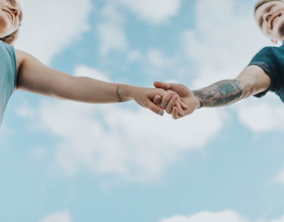 Imagen de una pareja sana y feliz tomada de la mano y riéndose juntos, representando una relación de pareja sana y feliz.