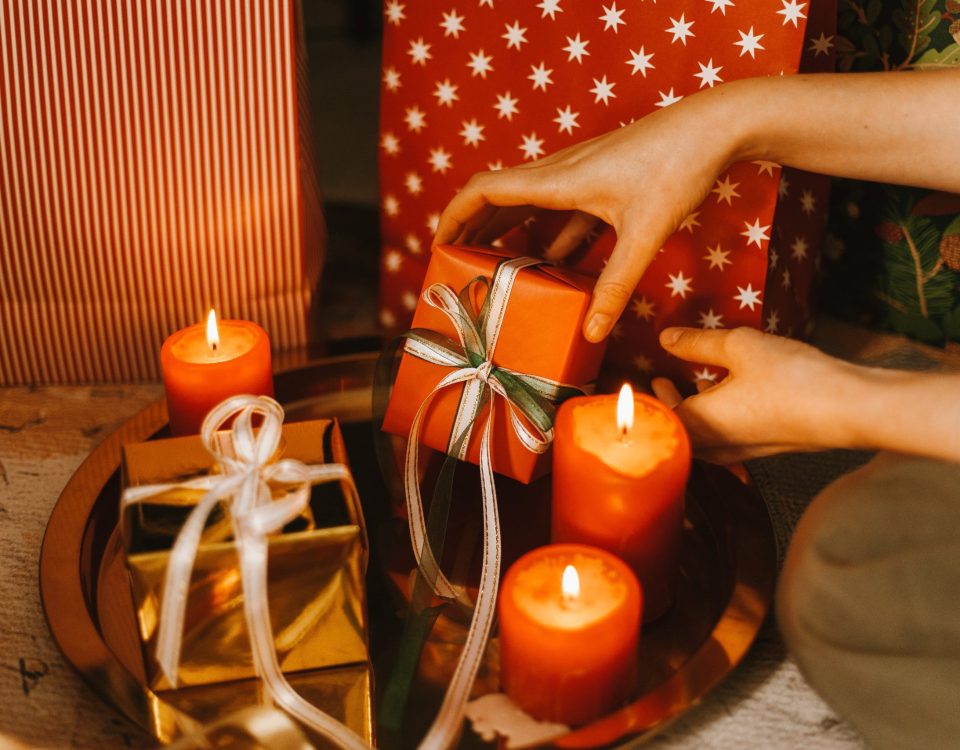 Vela iluminada junto a un regalo, simbolizando la conexión emocional y el bienestar en la psicología positiva durante las festividades.