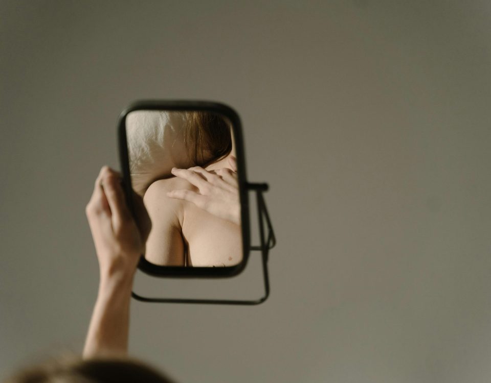 mujer viendo en el espejo y teniendo distorsión cognitiva de su imagen en la conducta alimentaria